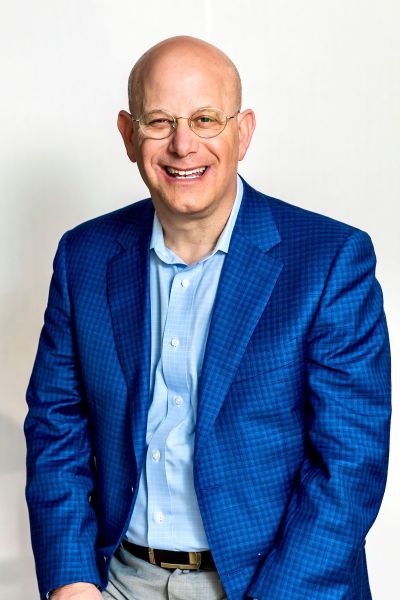 Headshot of a Jimmy Ringel with round glasses, wearing a vibrant blue blazer, working in Memphis corporate real estate.