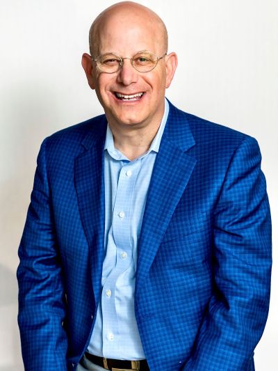 Headshot of a Jimmy Ringel with round glasses, wearing a vibrant blue blazer, working in Memphis corporate real estate.