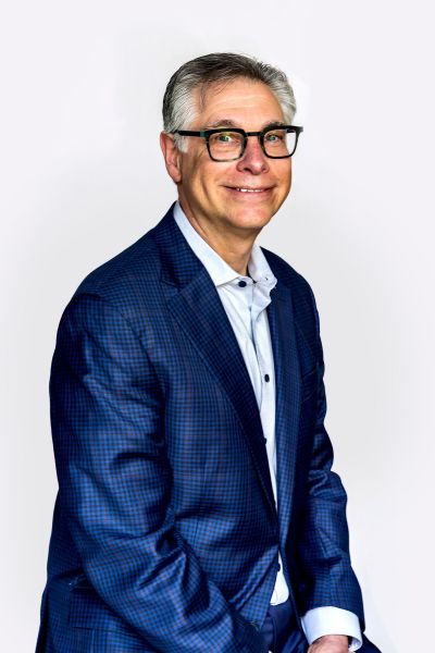 Professional headshot of Michael Greenberg wearing a blue plaid blazer and rectangular glasses,