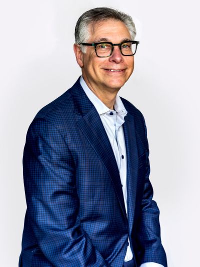 Professional headshot of Michael Greenberg wearing a blue plaid blazer and rectangular glasses,