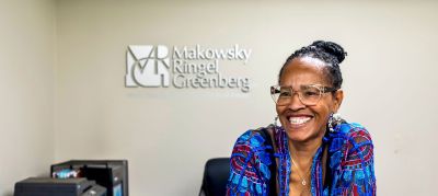 Smiling female professional seated in front of a Makowsky Ringel Greenberg office logo in the Memphis corporate real estate industry.