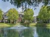 Lush green lawn and pond fountain framed by trees and brick apartment buildings at Westbury Apartments