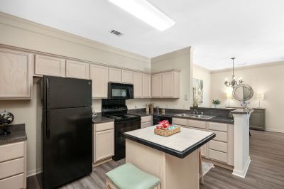 Model apartment kitchen interior at Westbury Apartments featuring black appliances, light wood cabinets, and a prep island