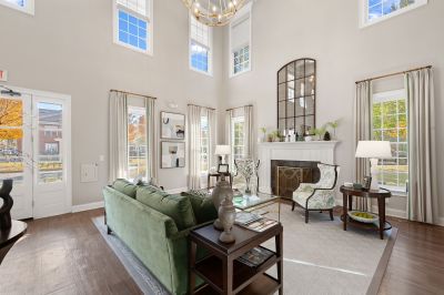 Spacious clubhouse sitting room at Westbury Apartments featuring vaulted ceilings, large windows, a fireplace, and green seating
