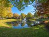 Picturesque pond and fountain reflecting autumn trees surrounding Westbury Apartments