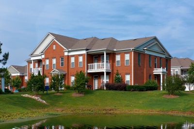 Exterior view of brick residential buildings with private balconies at Westbury Apartments set near a scenic pond