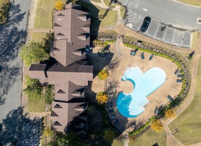 Aerial drone view showing apartment building rooflines and pool amenities