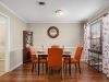 Staged model apartment dining room with vibrant orange chairs and hardwood floors