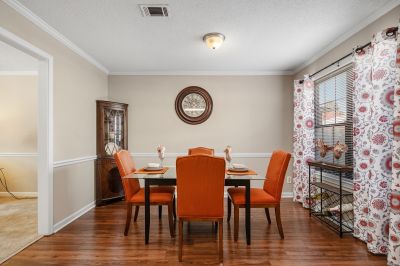 Staged model apartment dining room with vibrant orange chairs and hardwood floors
